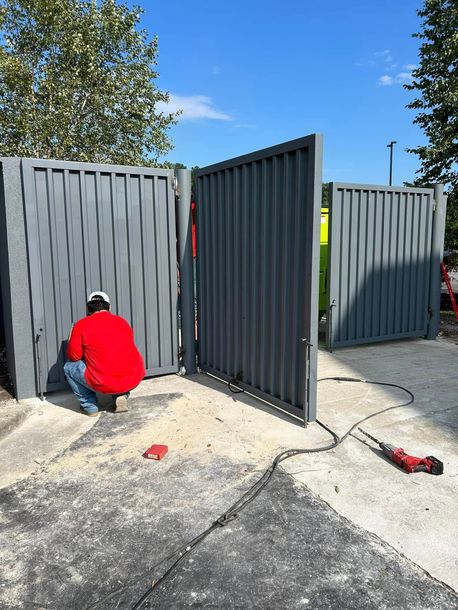 A man in a red shirt is working on a gate.