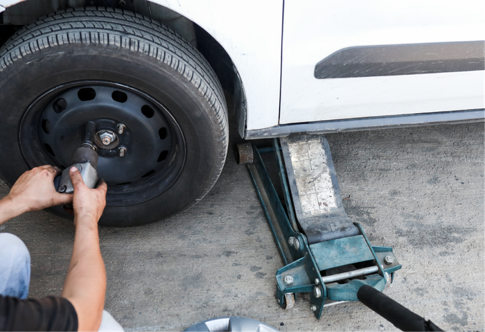 A man is changing a tire on a white van.