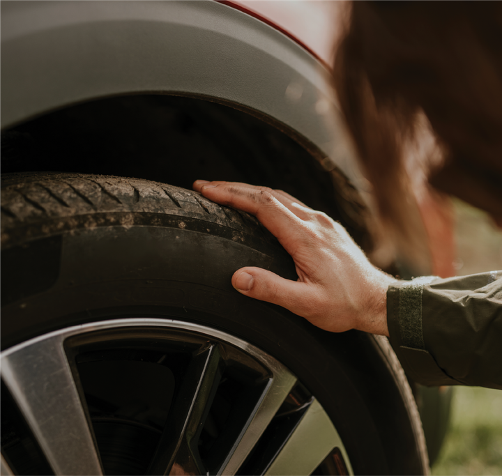 A person is touching the tire of a car