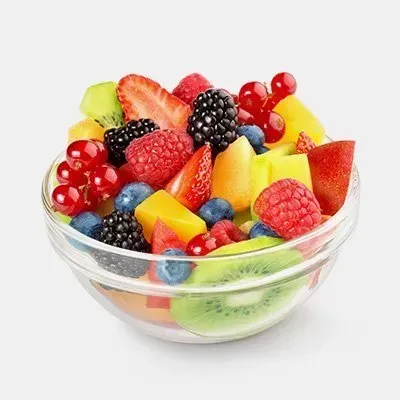 A glass bowl filled with sliced fruit on a white background.