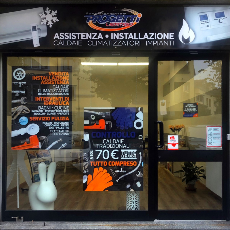 Vetrina con insegne pubblicitarie di servizi di riscaldamento e aria condizionata. Il nome del negozio è