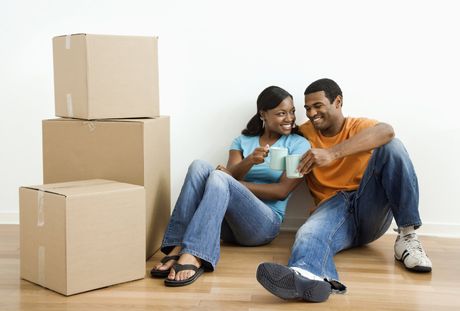 African American male and female couple sitting on floor next to moving boxes relaxing.