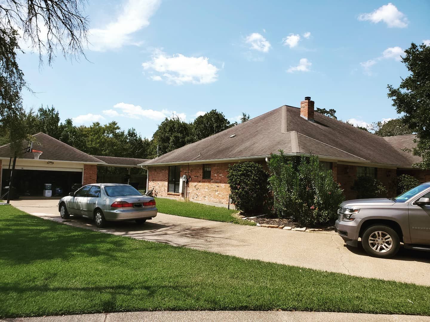 Two cars are parked in front of a brick house