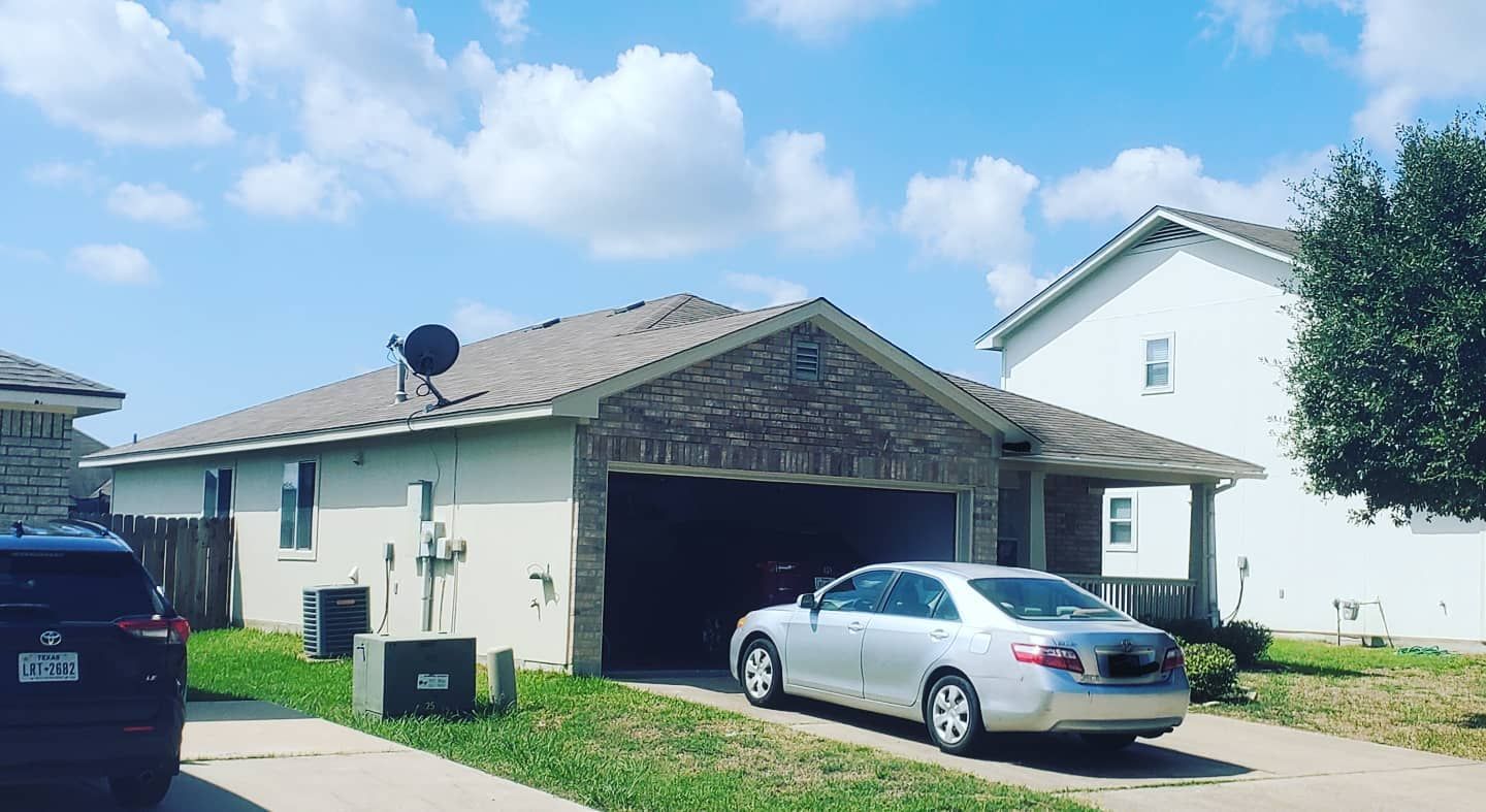 A silver car is parked in front of a white house.