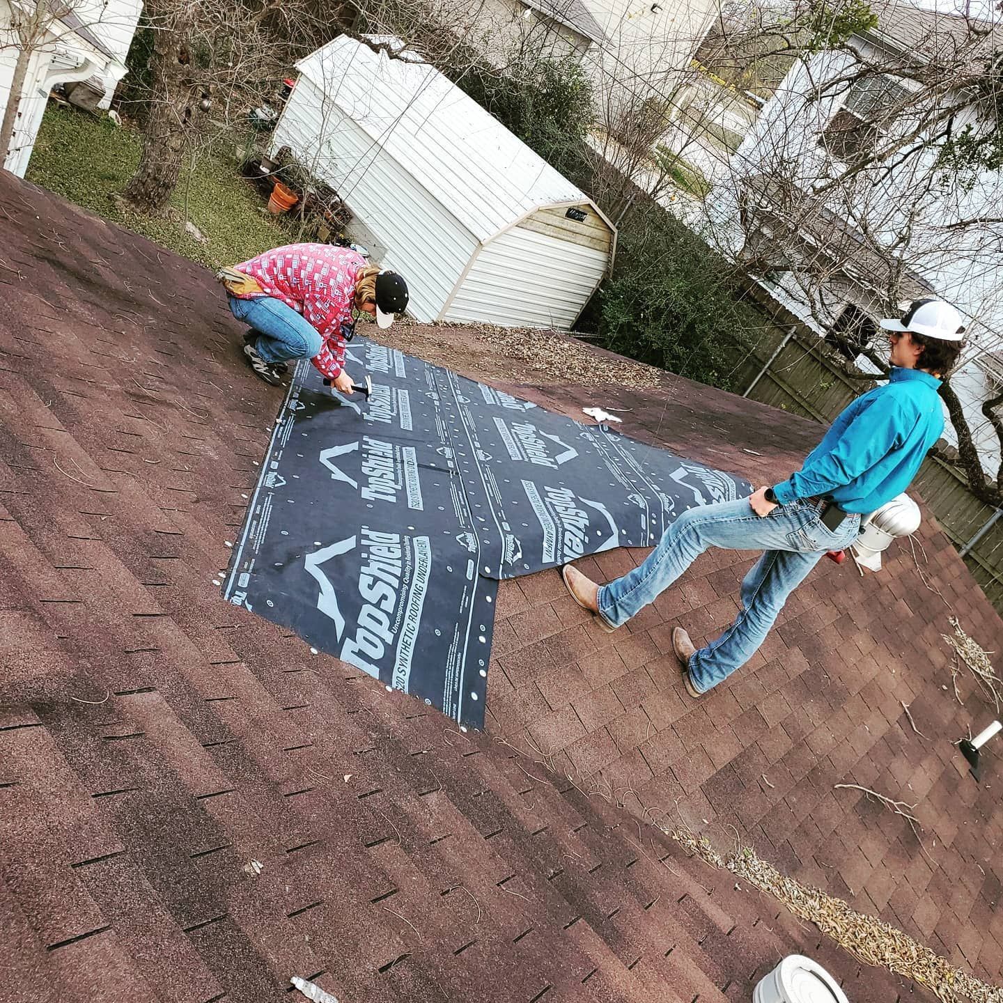 A couple of people are working on a roof.