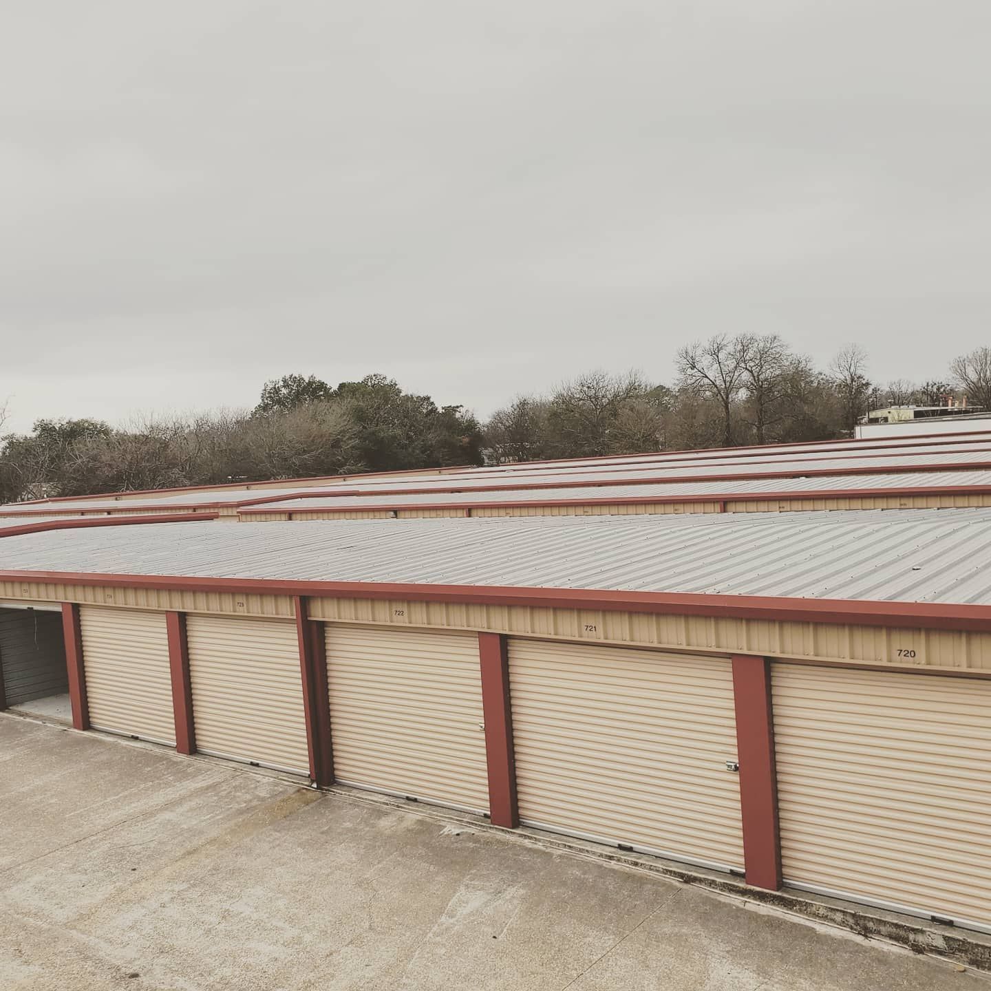 A row of garage doors with a metal roof on a cloudy day