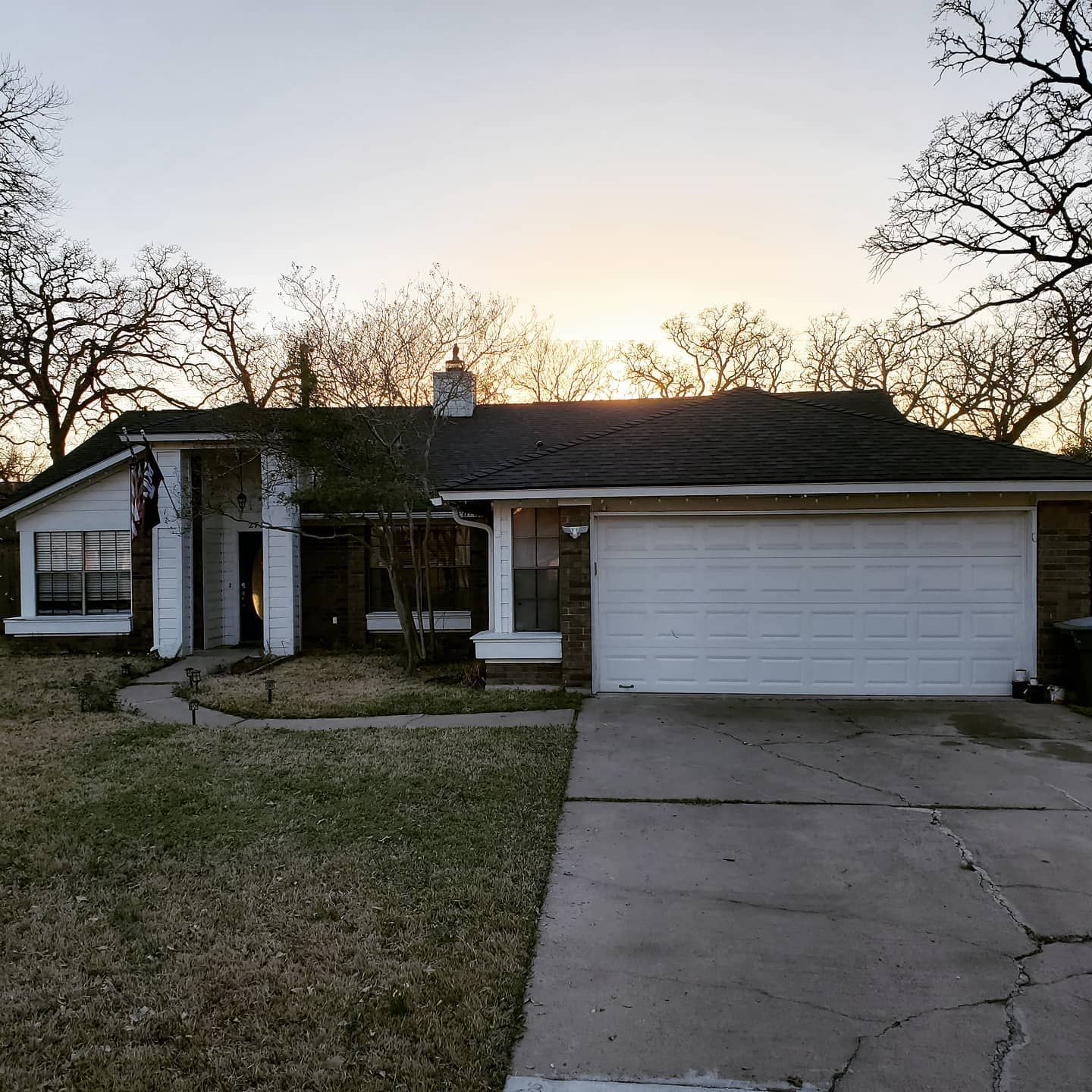 A house with a white garage door and a sunset in the background