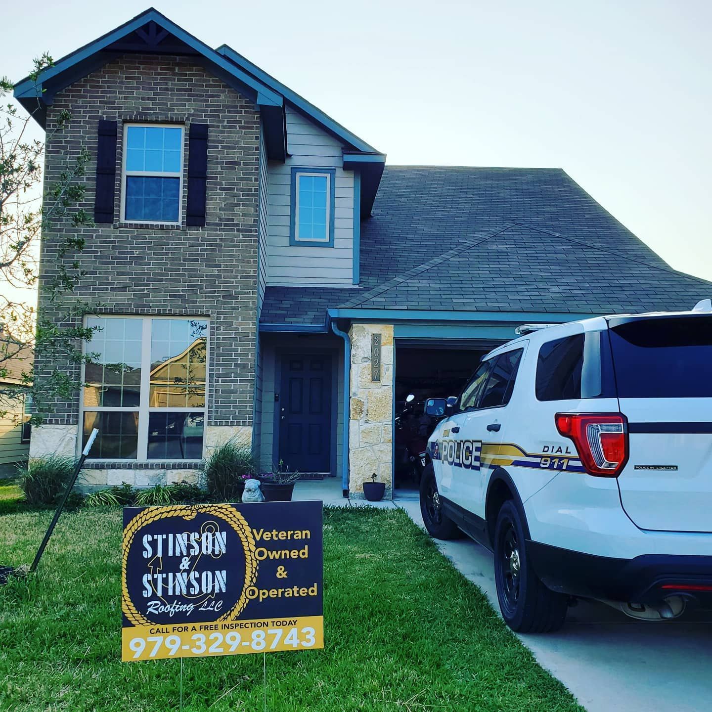 A white police car is parked in front of a house