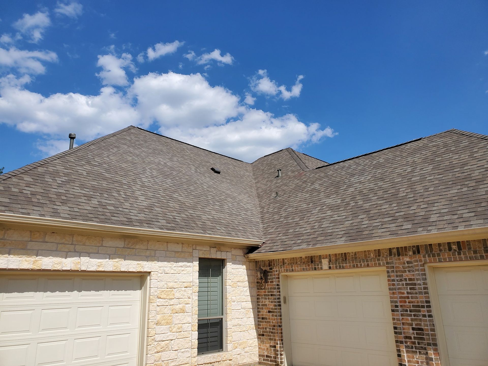 A house with two garage doors and a roof with a blue sky in the background.