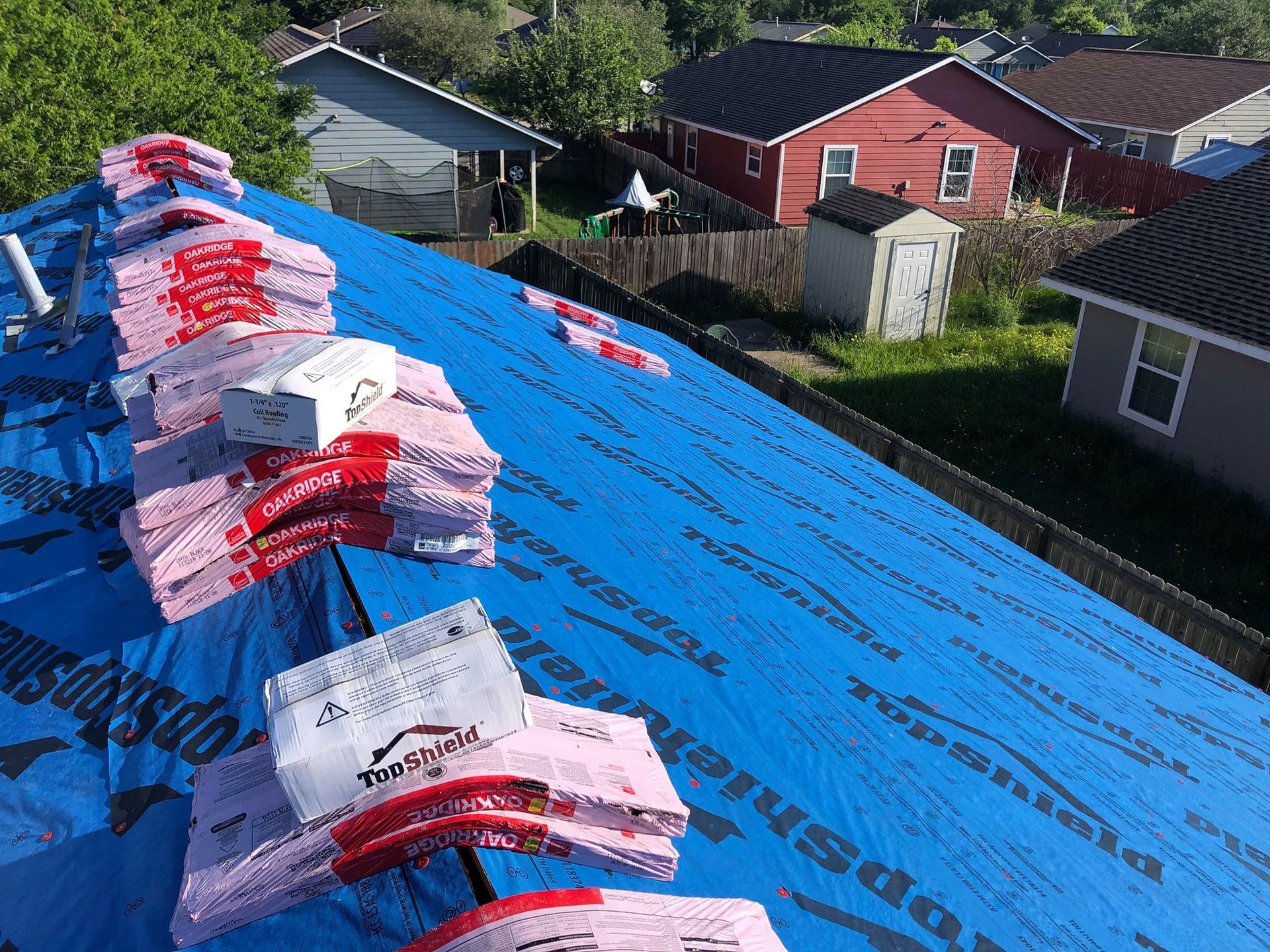 A roof with a lot of bags of roofing material on it.