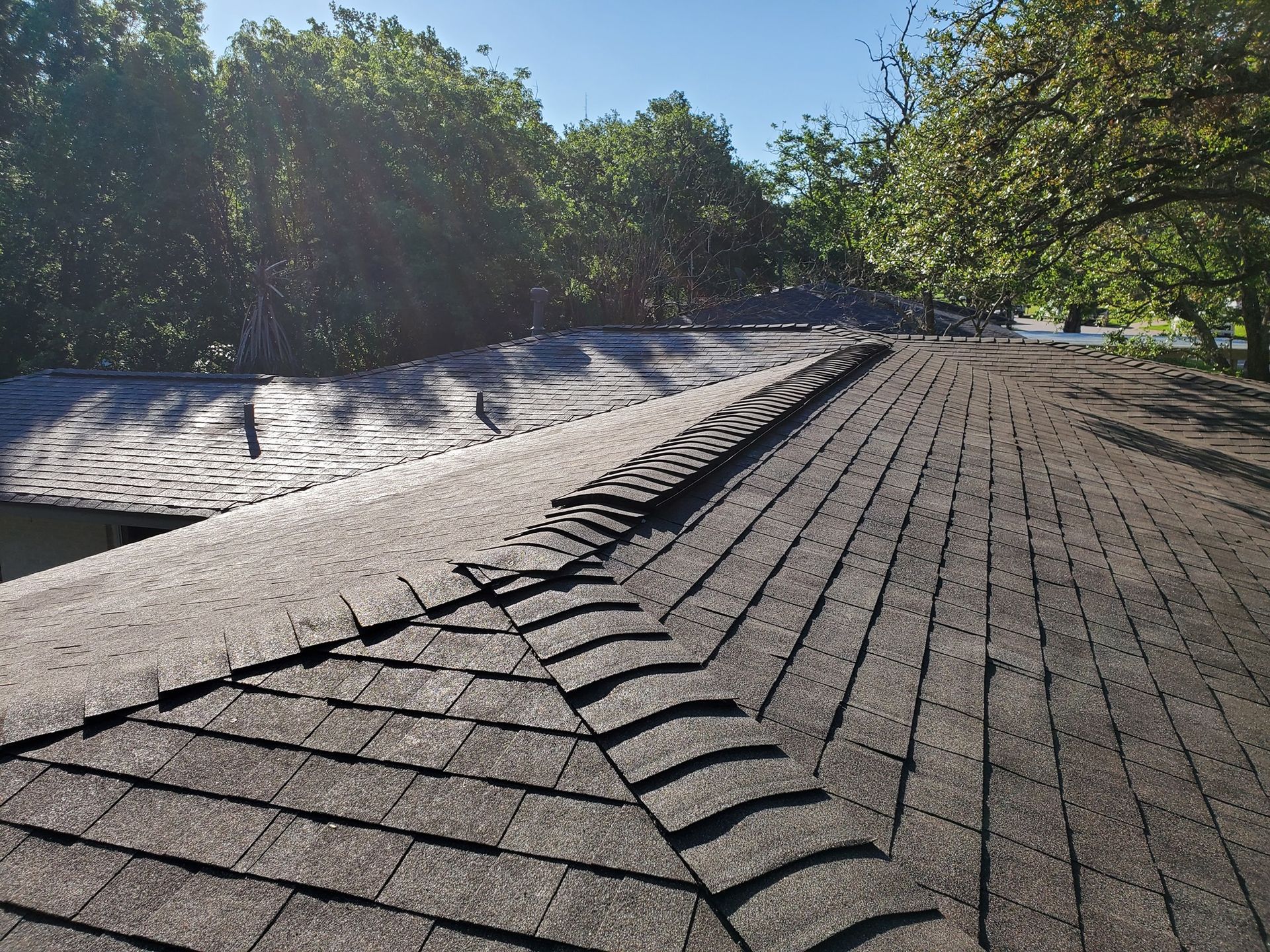 A roof with a lot of shingles on it and trees in the background.