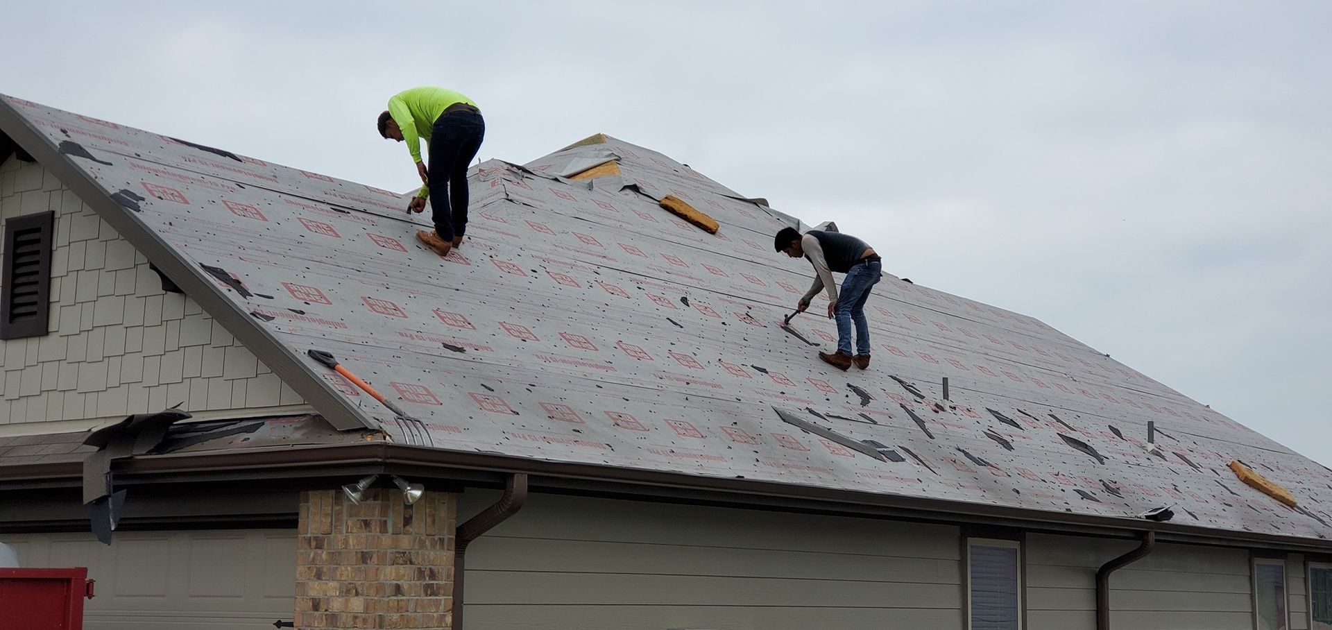 Two men are working on the roof of a house.