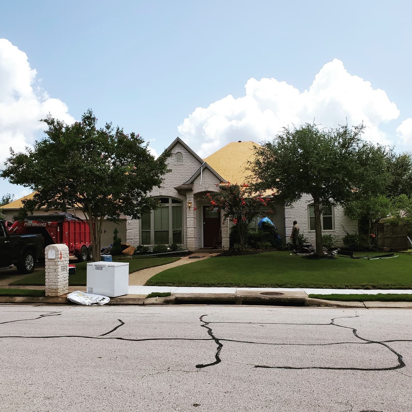 A white house with a yellow roof and a red truck parked in front of it