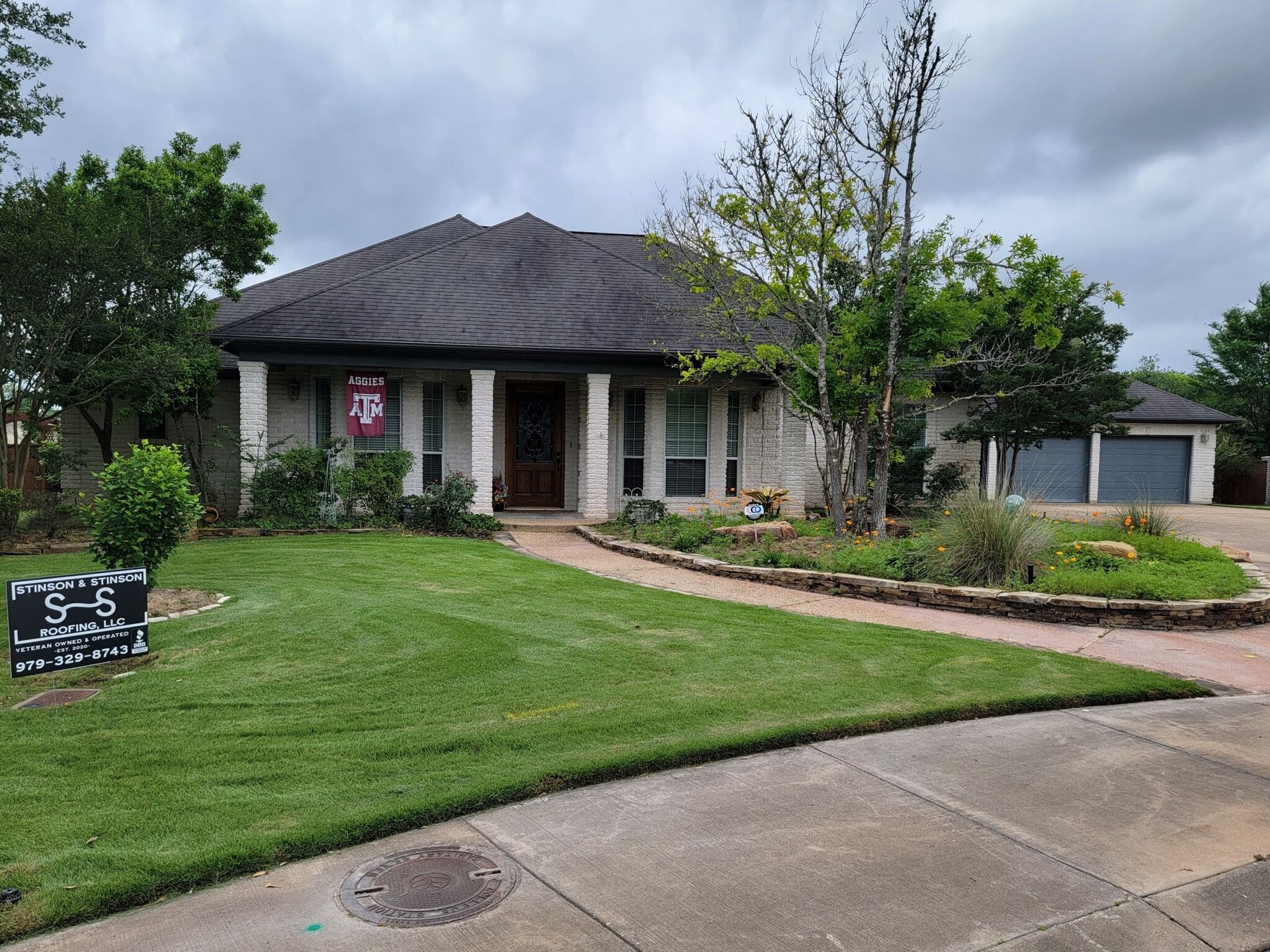 A house with a lush green lawn and a for sale sign in front of it.