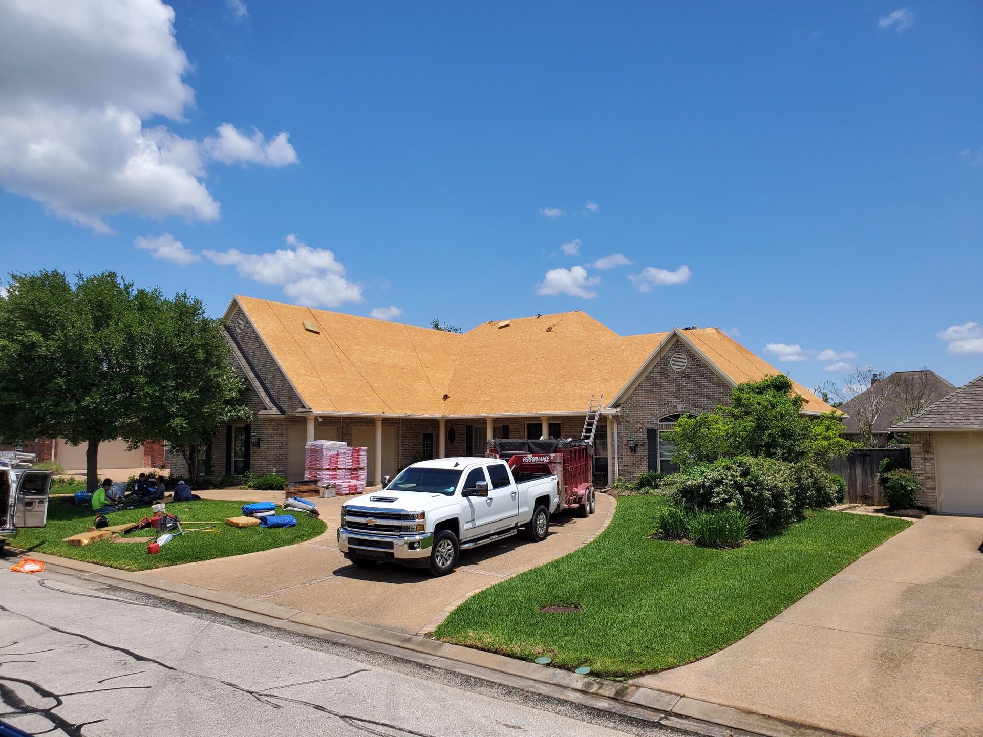 A white truck is parked in front of a house with a new roof.