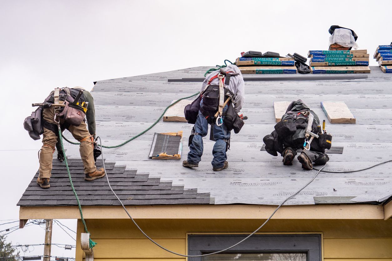 A group of men are working on the roof of a house.