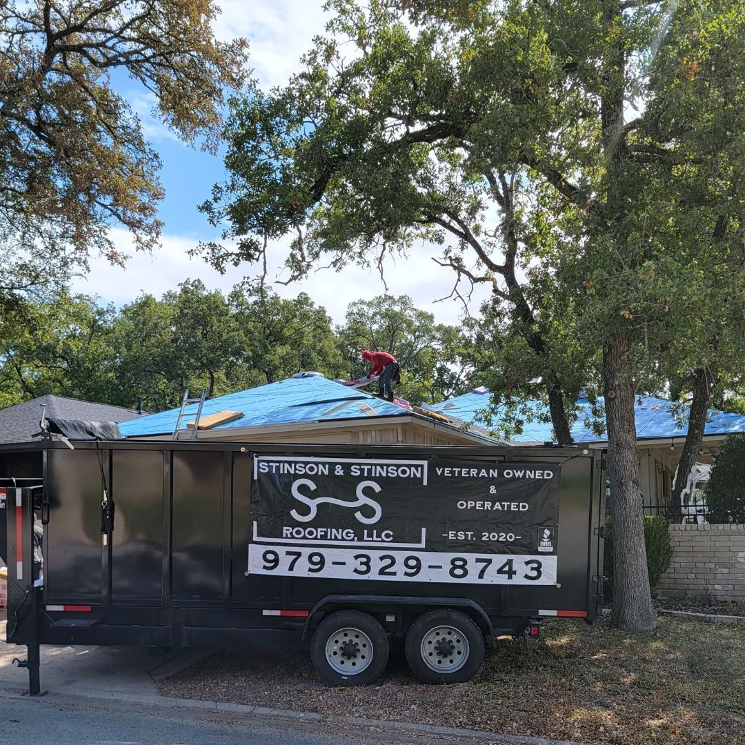 A trailer is parked in front of a house with a man standing on top of it.