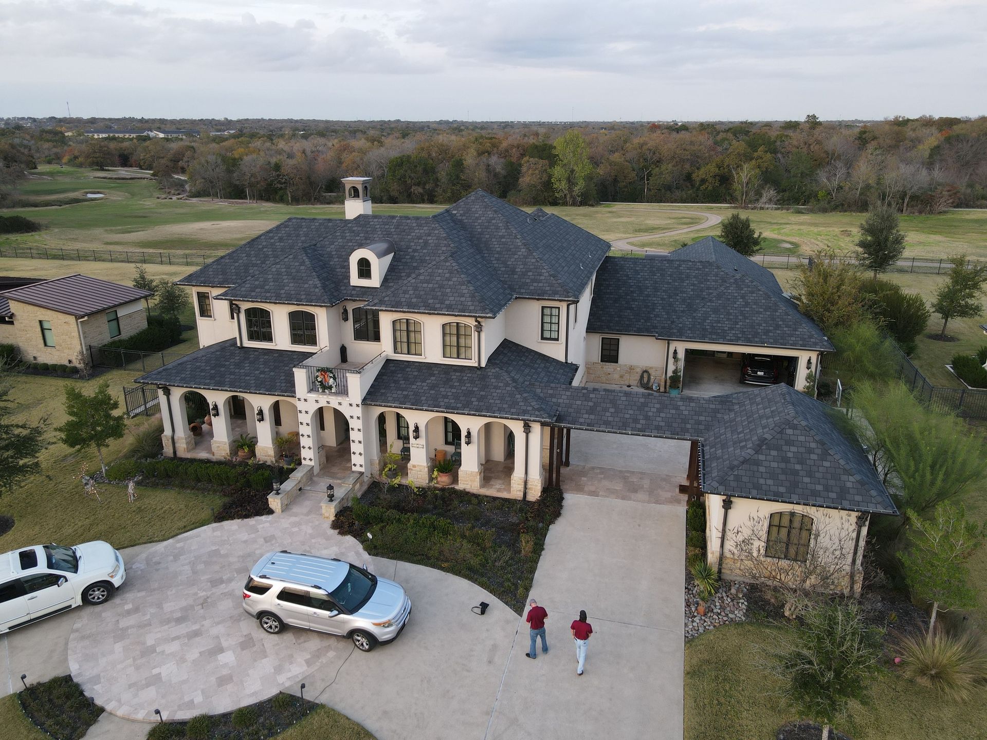 An aerial view of a large house with cars parked in front of it.