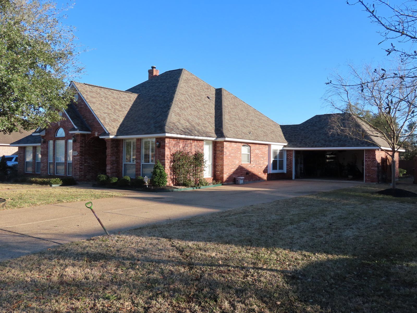 A large brick house with a gray roof and a large driveway