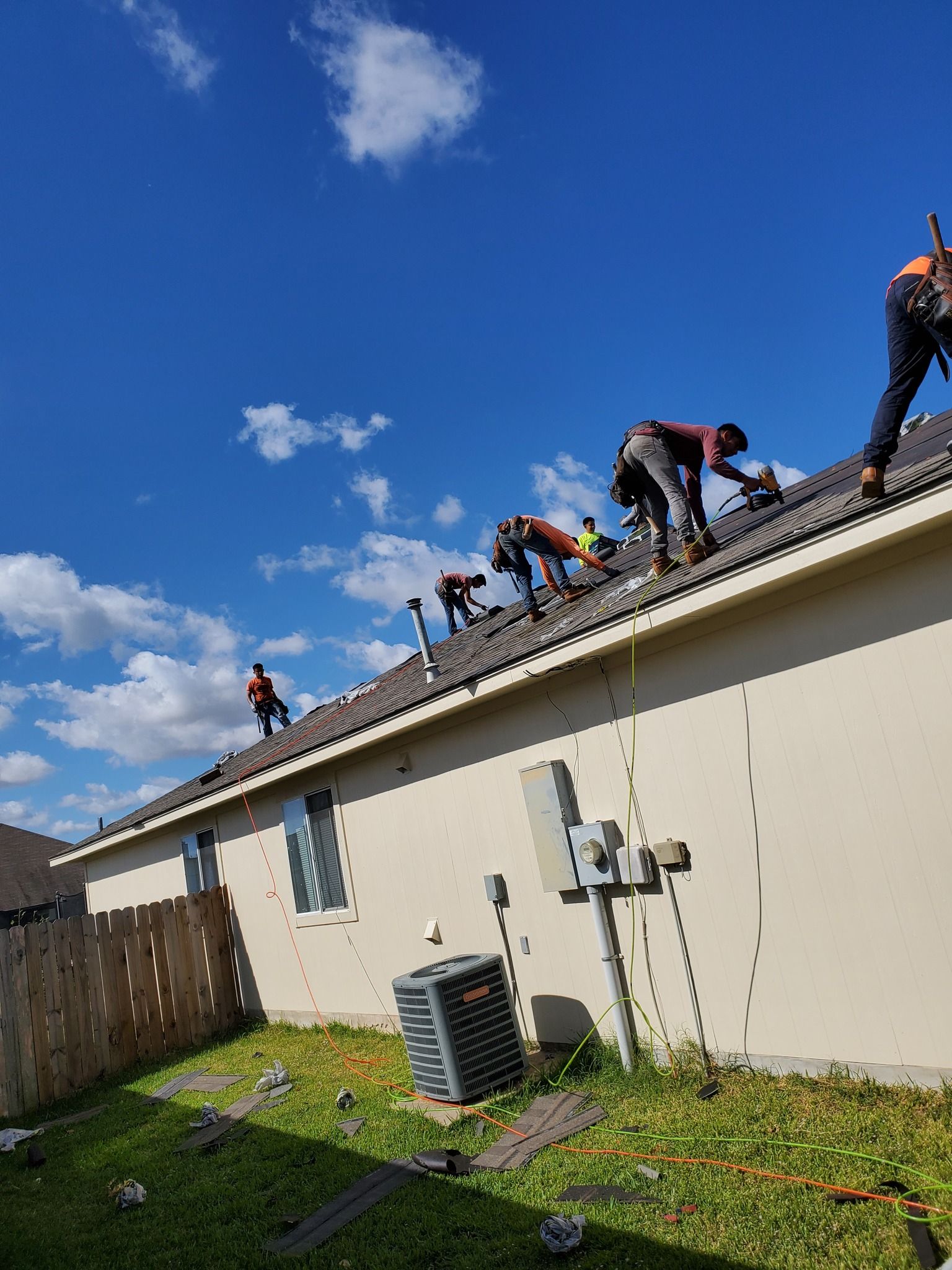 A group of men are working on the roof of a house.