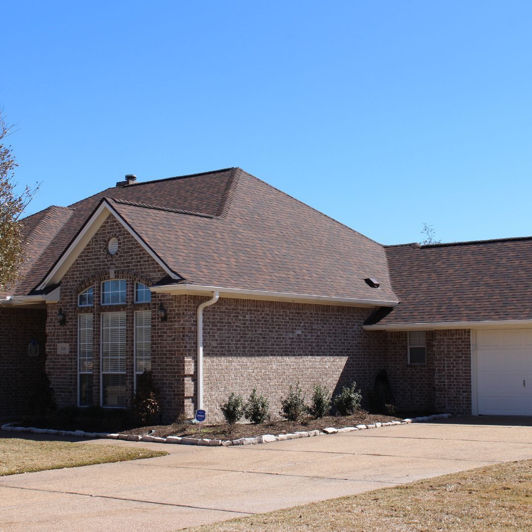 A brick house with a brown roof and a white garage door
