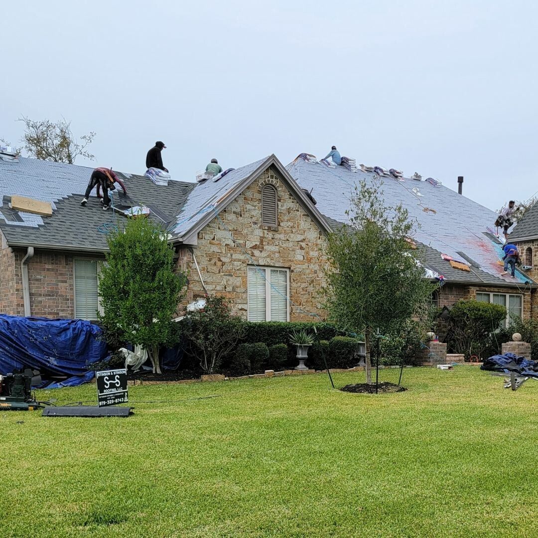 A group of people are working on the roof of a house.