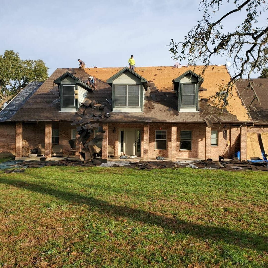 Two men are working on the roof of a house.