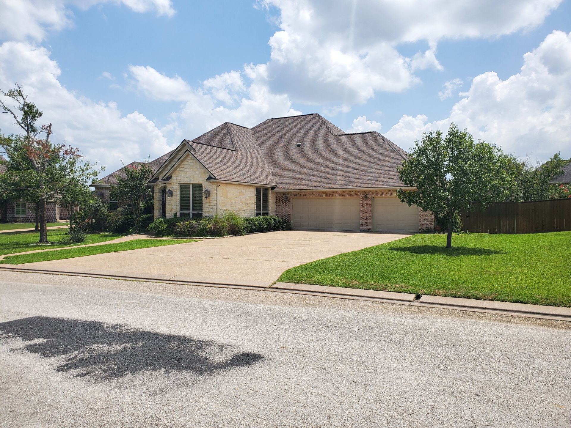 A large white house with a brown roof is sitting on top of a lush green lawn.