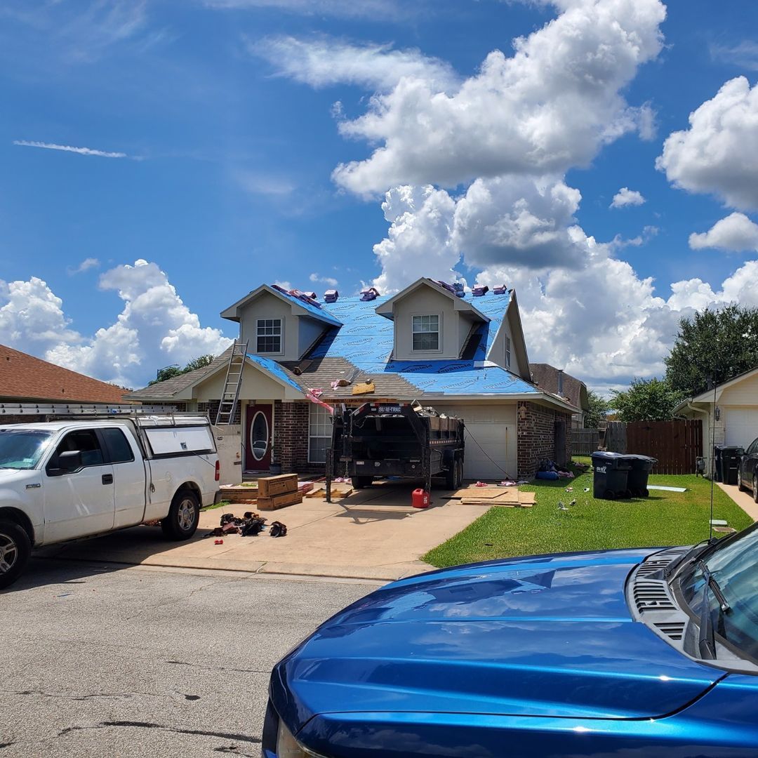 A blue truck is parked in front of a house with a blue roof.