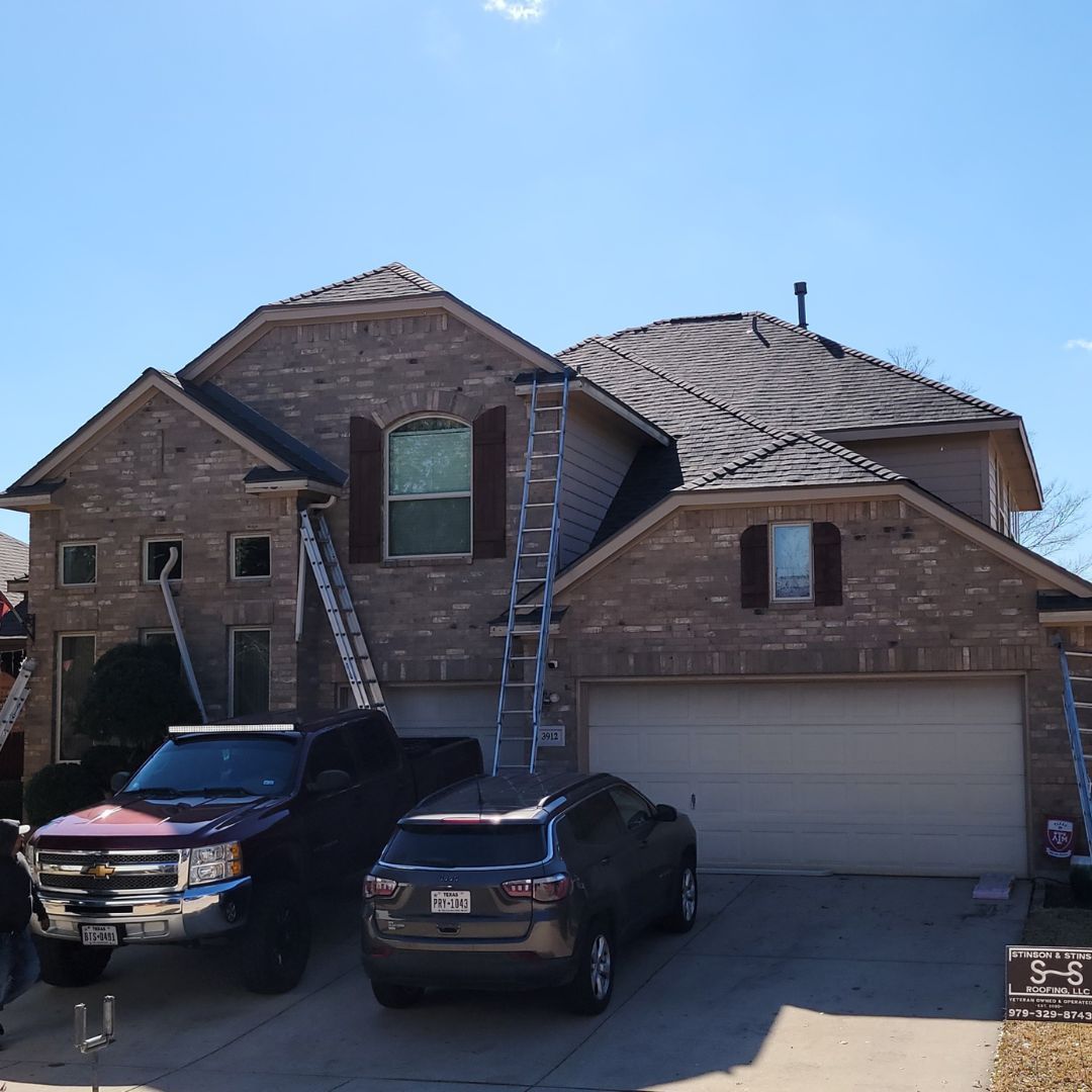 A brick house with two cars parked in front of it