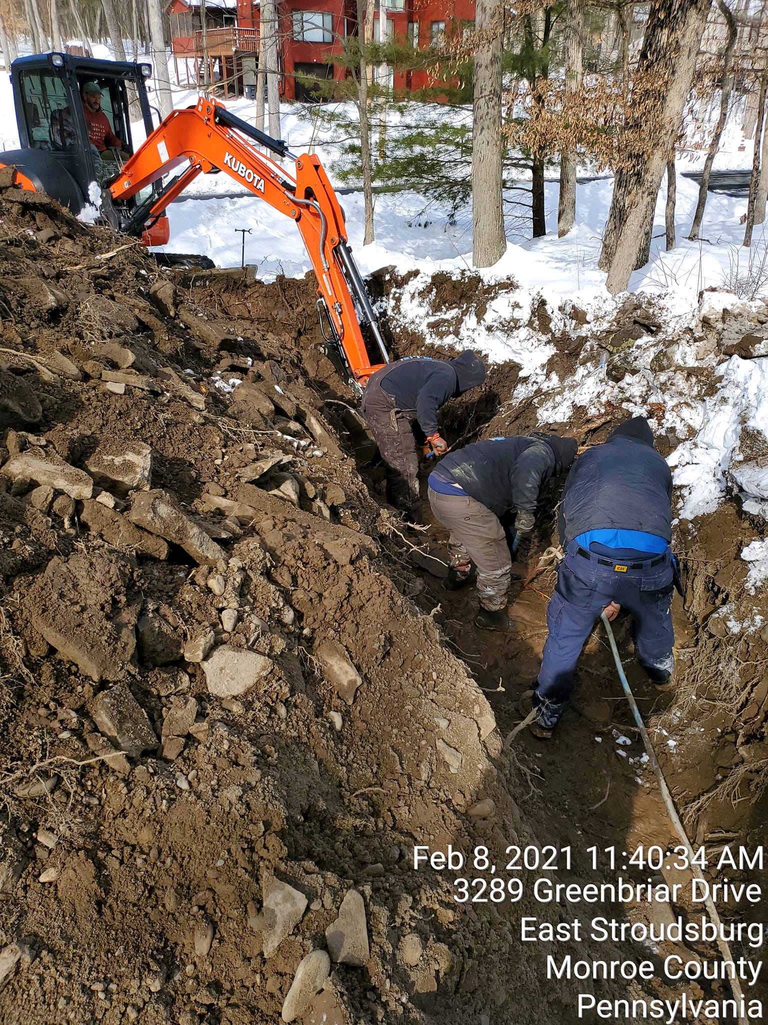 A group of men are digging a hole in the ground in the snow.