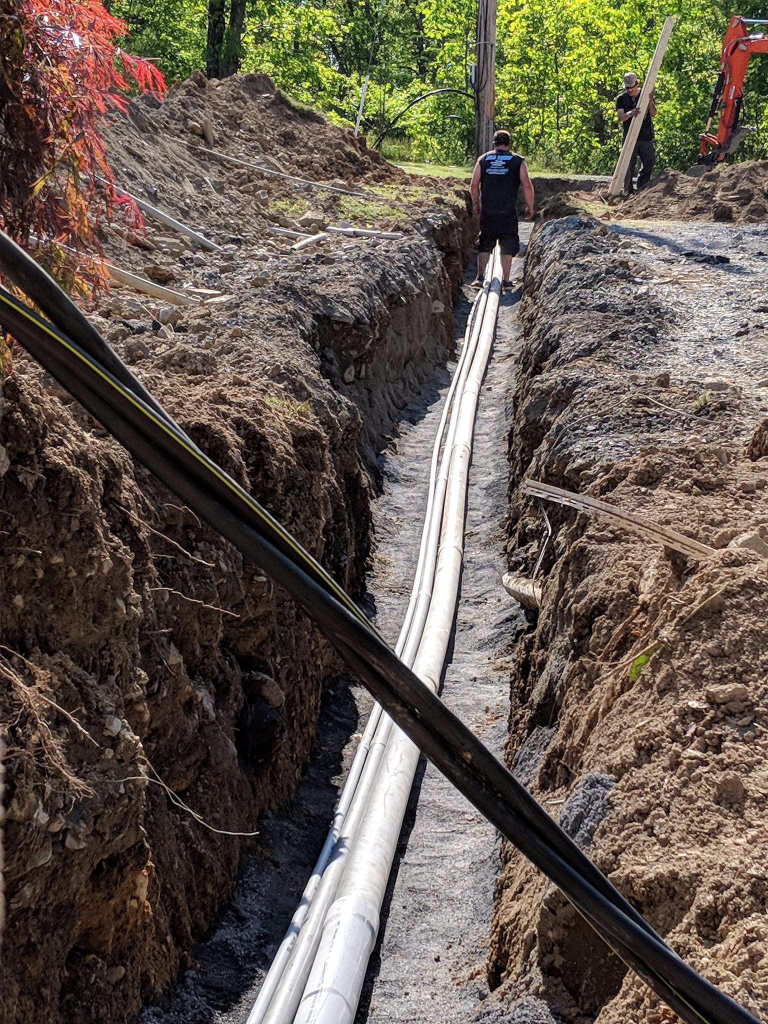 A man is standing in a trench next to a pipe.