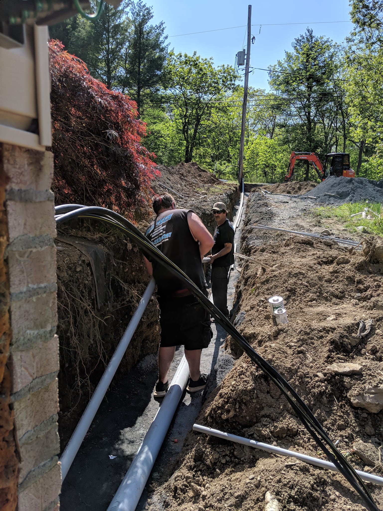 A man is standing next to a pile of pipes in the dirt.