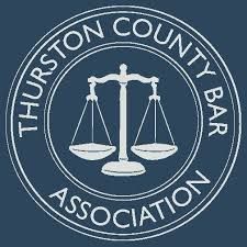 The logo for the thurston county bar association is a scale of justice in a circle.