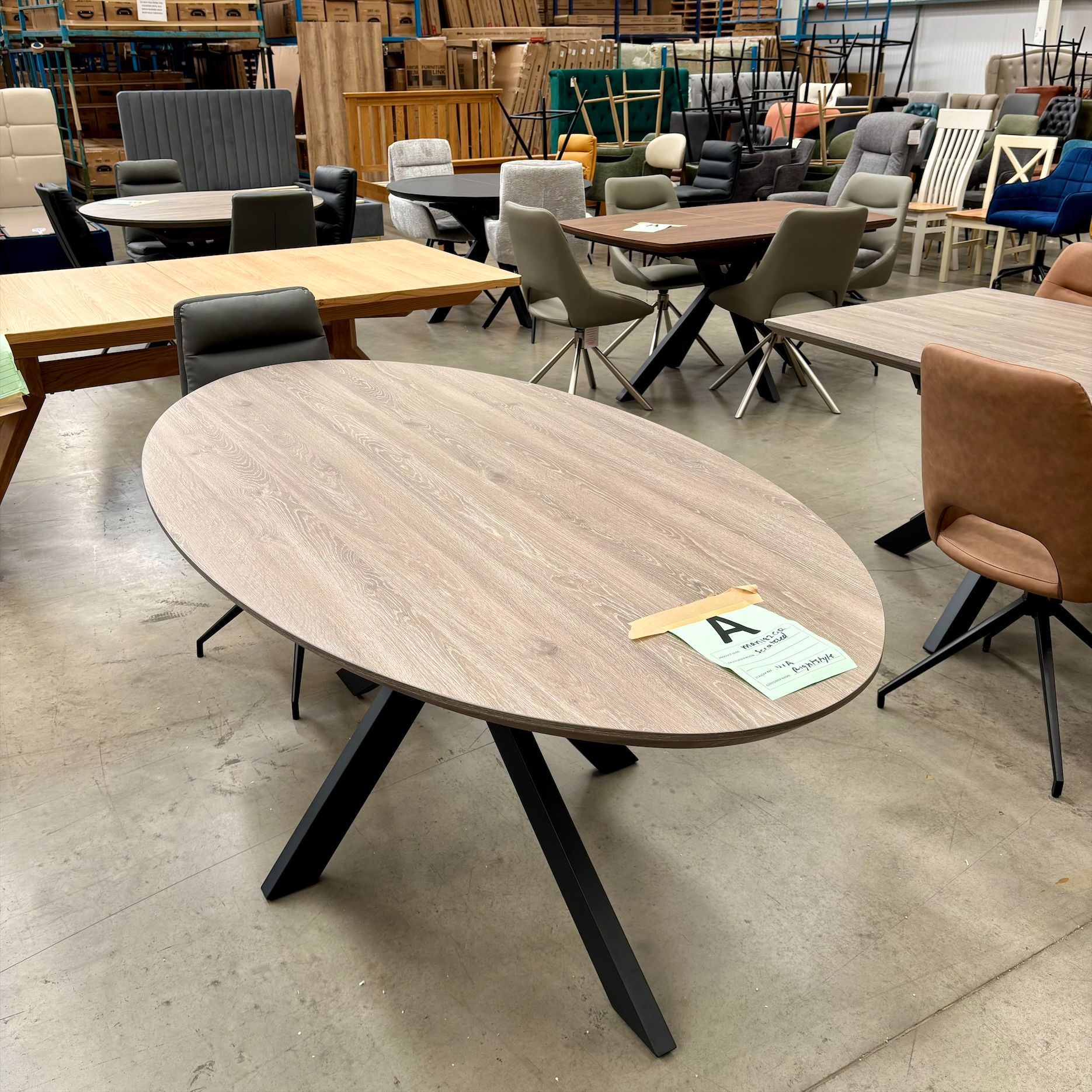 Furniture showroom with oval wooden table and assorted chairs on a concrete floor