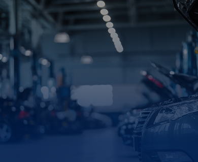 Cars in an auto repair shop, under blue lighting.