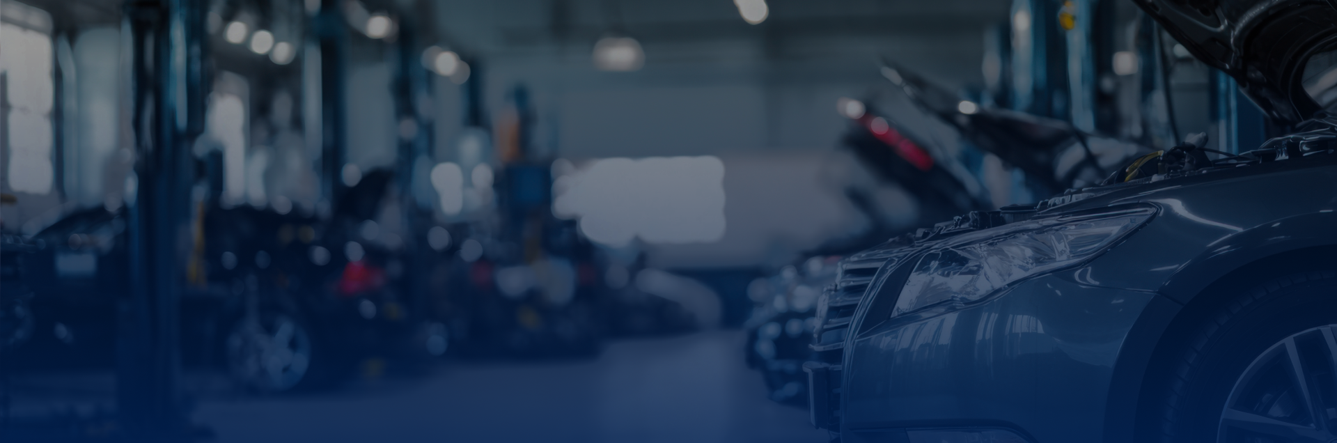 Cars in an auto repair shop with hoods up, possibly under maintenance.