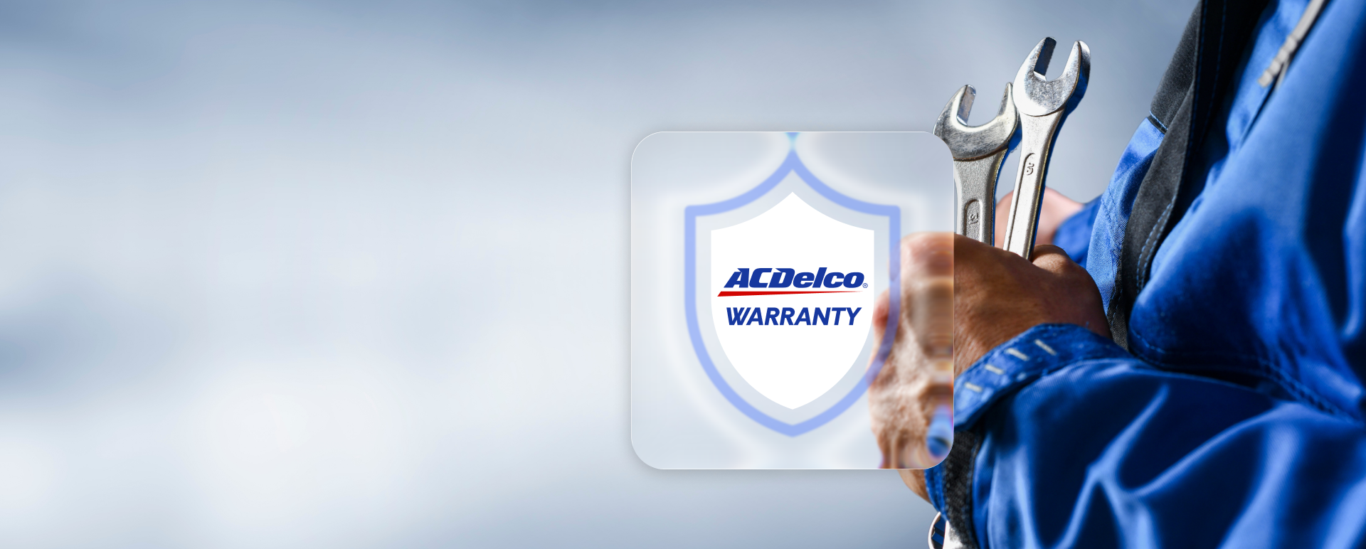 Mechanic holding a wrench next to a warranty badge on a blurred background.