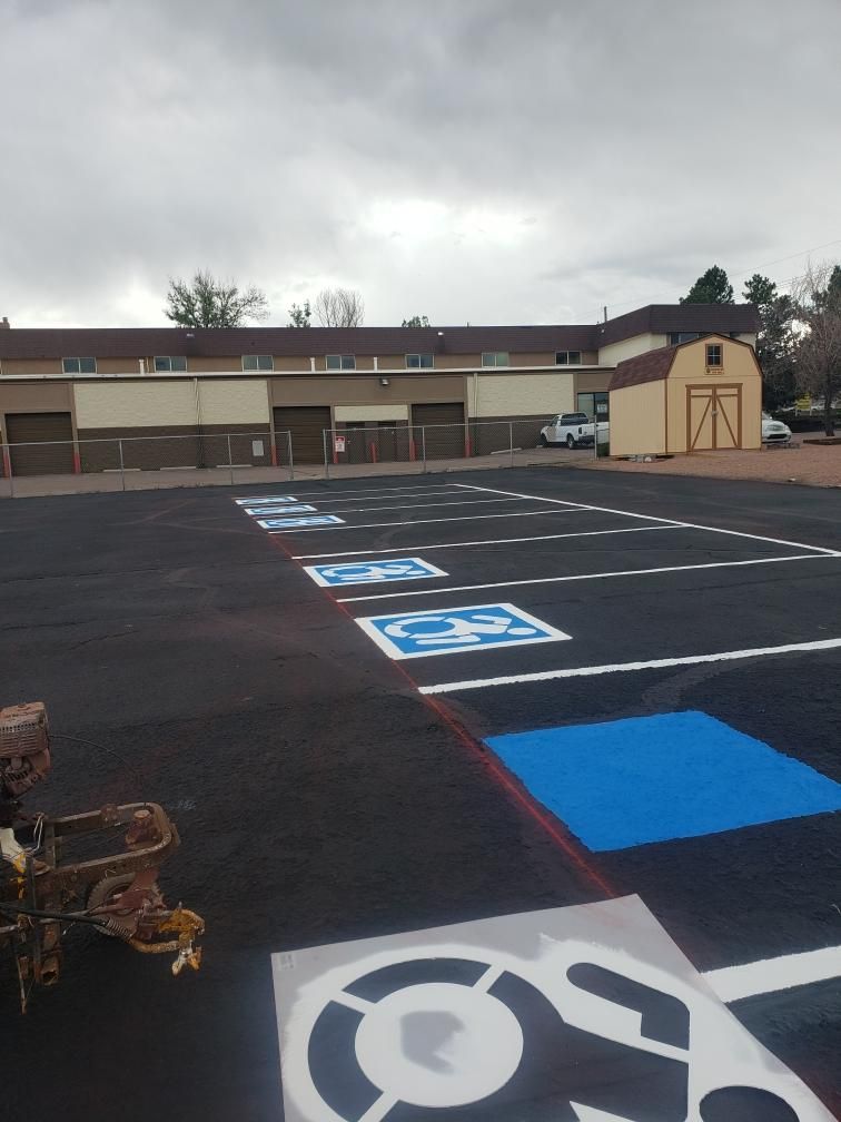 Newly painted accessible parking spaces in a lot. Blue and white wheelchair symbols on black asphalt.