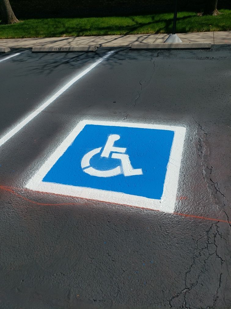 Blue and white handicap symbol painted on asphalt parking space.