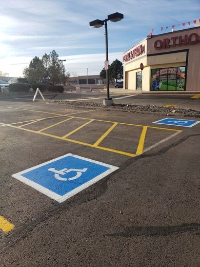 Parking lot with painted blue handicap symbols and yellow lines, next to a store.