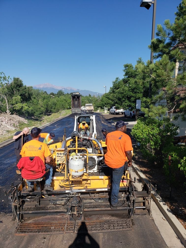 Road paving in progress. Workers operating asphalt paver, sunny day.