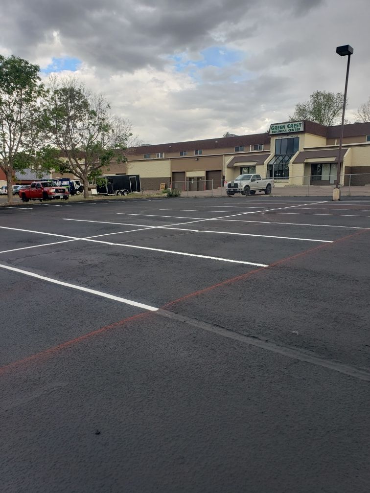 Empty parking lot in front of a building under a cloudy sky.