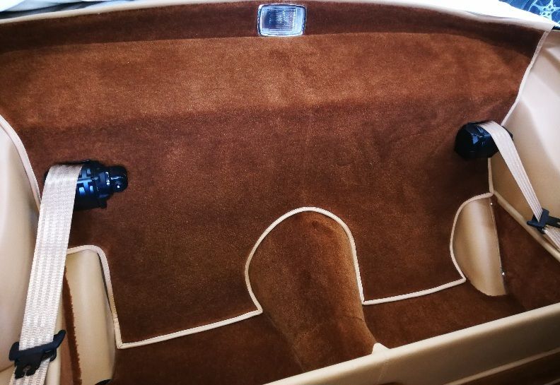 Brown car interior with tan seatbelts, carpet, and trim.