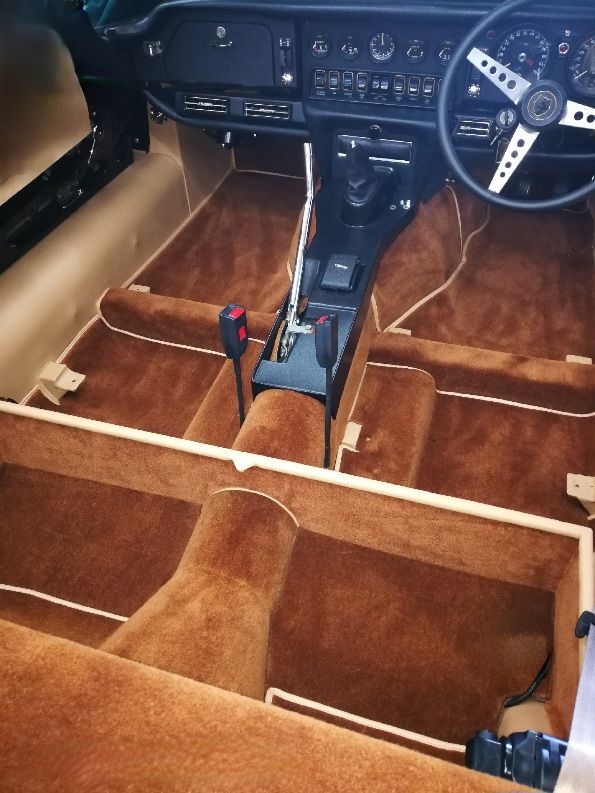 Interior view of a classic car with brown carpet and beige trim.