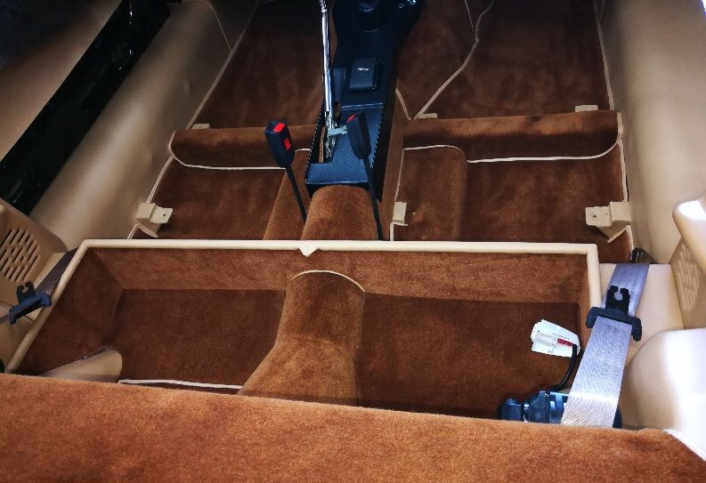 Brown car interior with carpet, beige trim, and a center console.