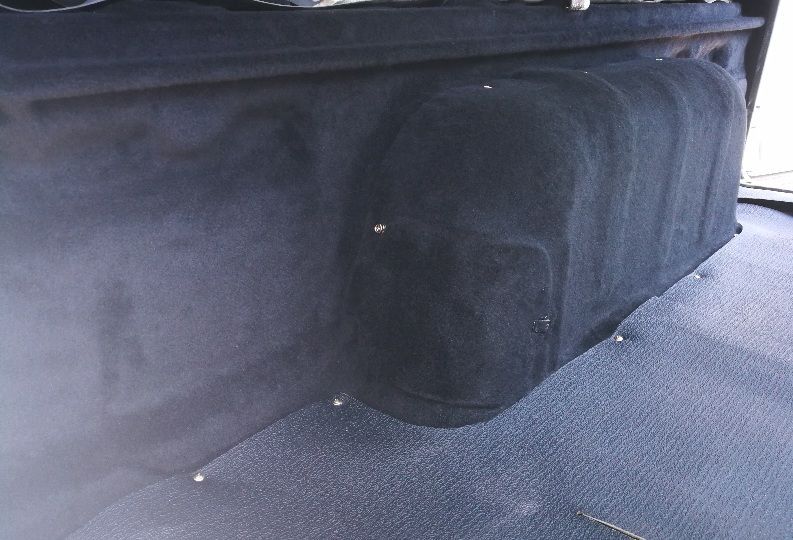 Dark, fuzzy car trunk interior with a box-like structure covered in the same material.
