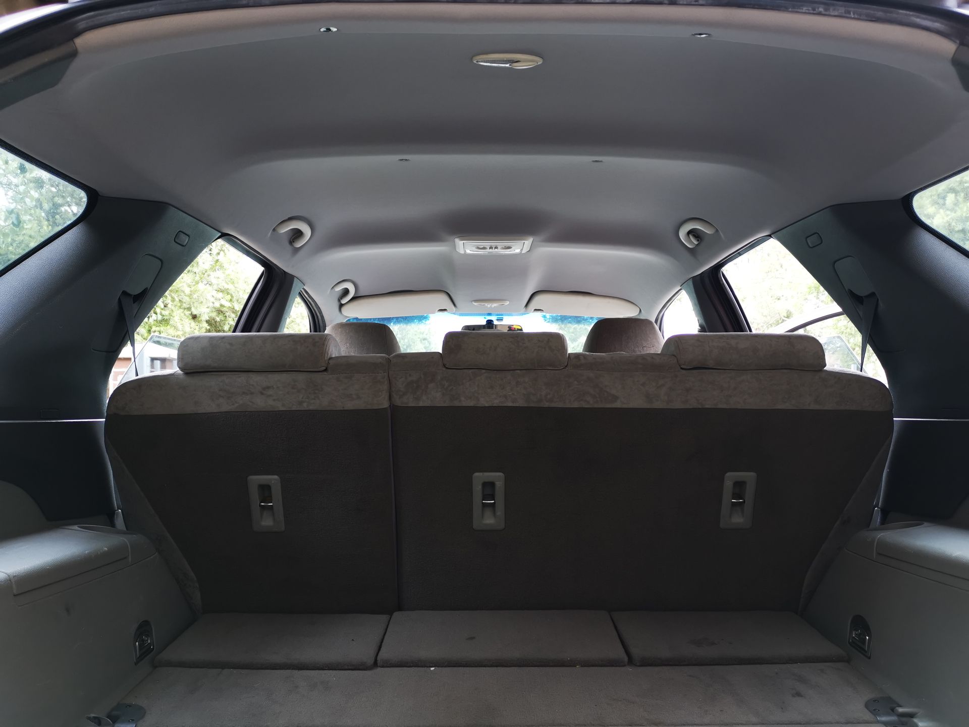Interior view of a car trunk with folded seats. Beige and brown colors dominate.