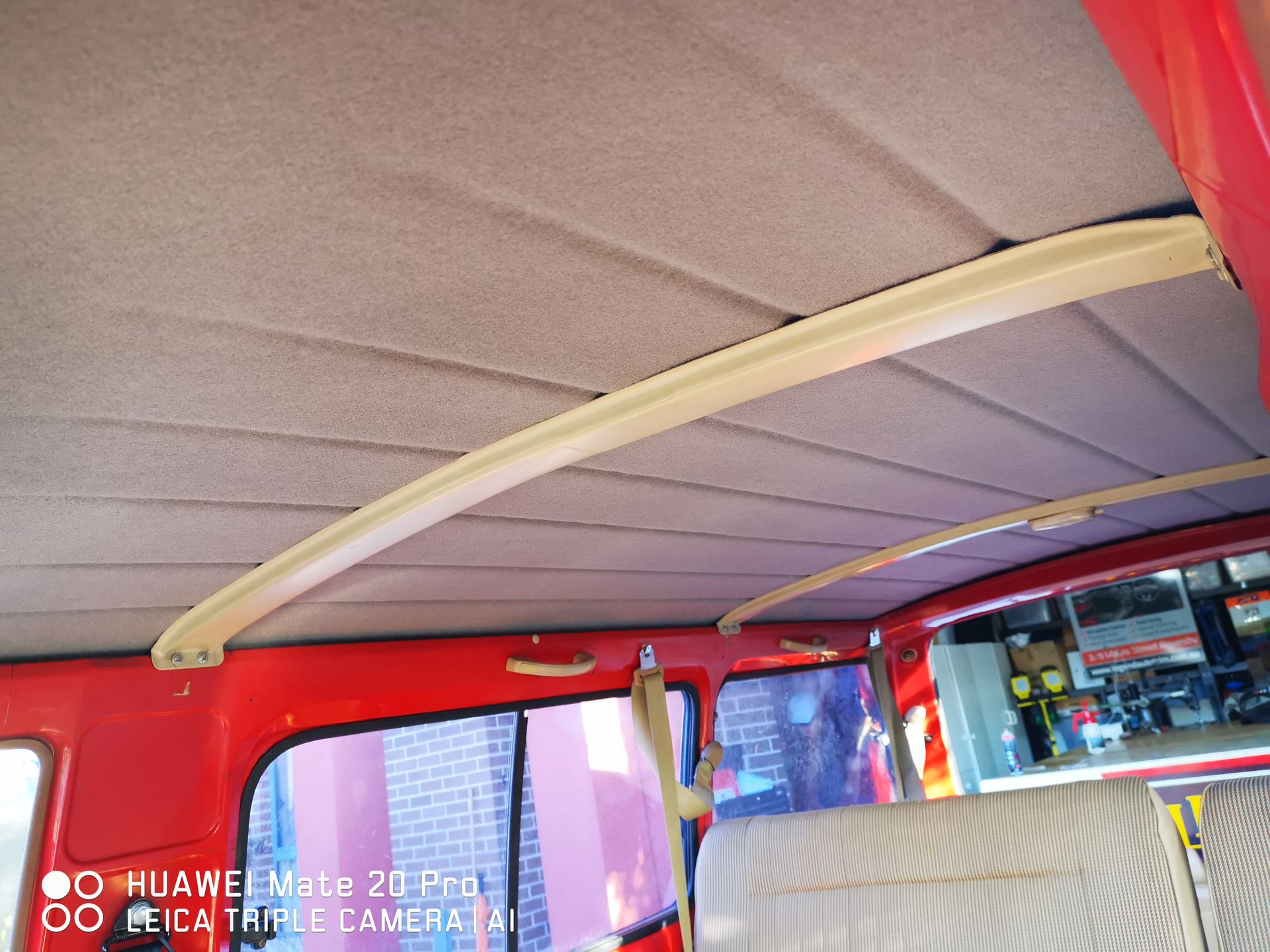 Tan headliner inside a red vehicle with curved, beige support beams.