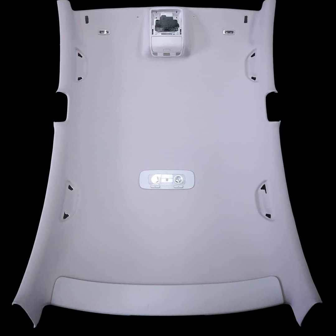 Pale gray car headliner with cutouts for lights and accessories.